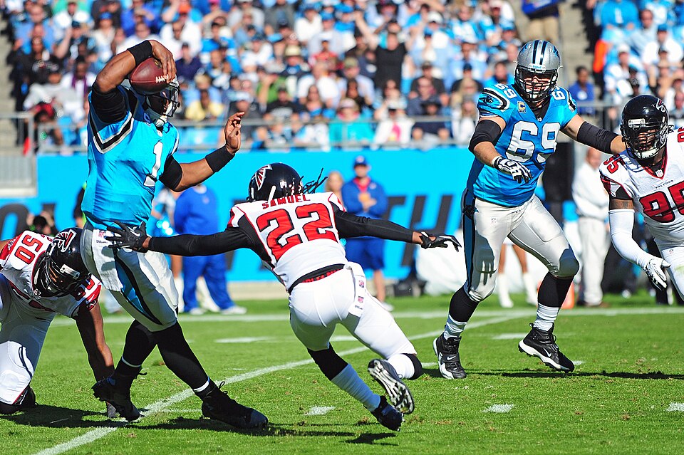 Action color photo of Cam Newton, Carolina Panthers quarterback, maneuvers around Asante Samuel, Atlanta Falcons cornerback, during a game at Bank of America Stadium in Charlotte, N.C., Nov. 3, 2013. Prior to the start of the game, five members of Team Seymour were recognized for their service. (U.S. Air Force photo by Airman 1st Class John Nieves Camacho)