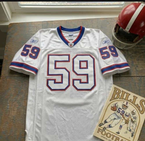 Vintage Buffalo Bills #59 football jersey as seen in Fletcher_59.jpg. White mesh with royal blue and red shadowed block numbers. Includes a red Bills helmet and an official gameday program for historical NFL research on linebacker London Fletcher for Pigskin Dispatch archives.