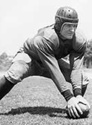 Vintage black and white image of Ki Aldrich in full uniform, ready to snap the football. This image is used under non-free fair use as it is of a deceased subject of historical significance, and as such no replaceable substitute exists.