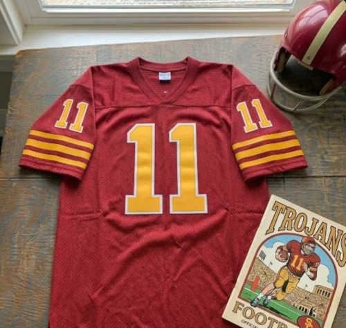 Red Number 11 jersey with a red helmet and Trojans program cover