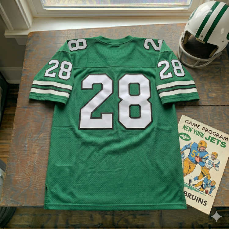 Vintage New York Jets #28 football jersey. Gotham Green mesh with white and black shadowed block numbers and triple-striped sleeves. Features a New York Jets game program and a white helmet with green stripes for historical NFL research and Pigskin Dispatch archives.