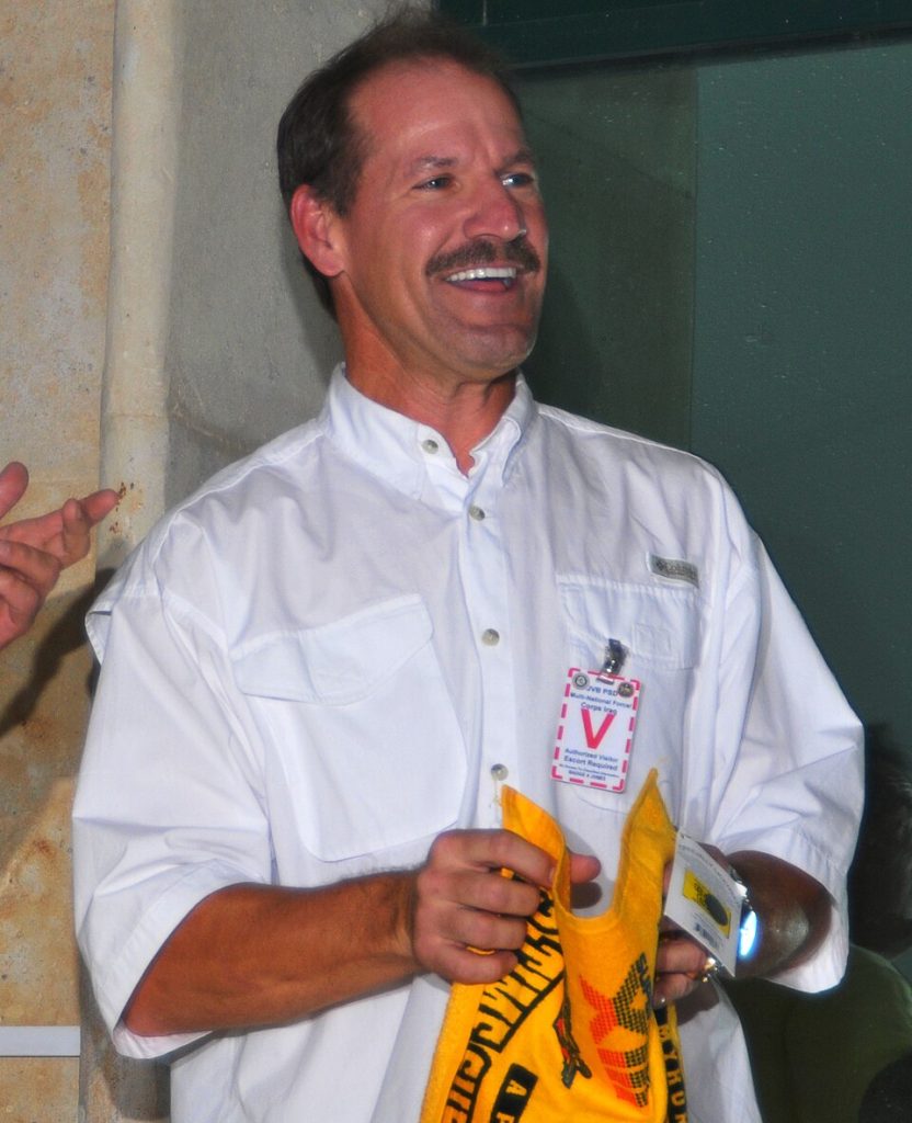 Color photo of Bill Cowher in a white button down shirt holding a yellow Terrible Towel