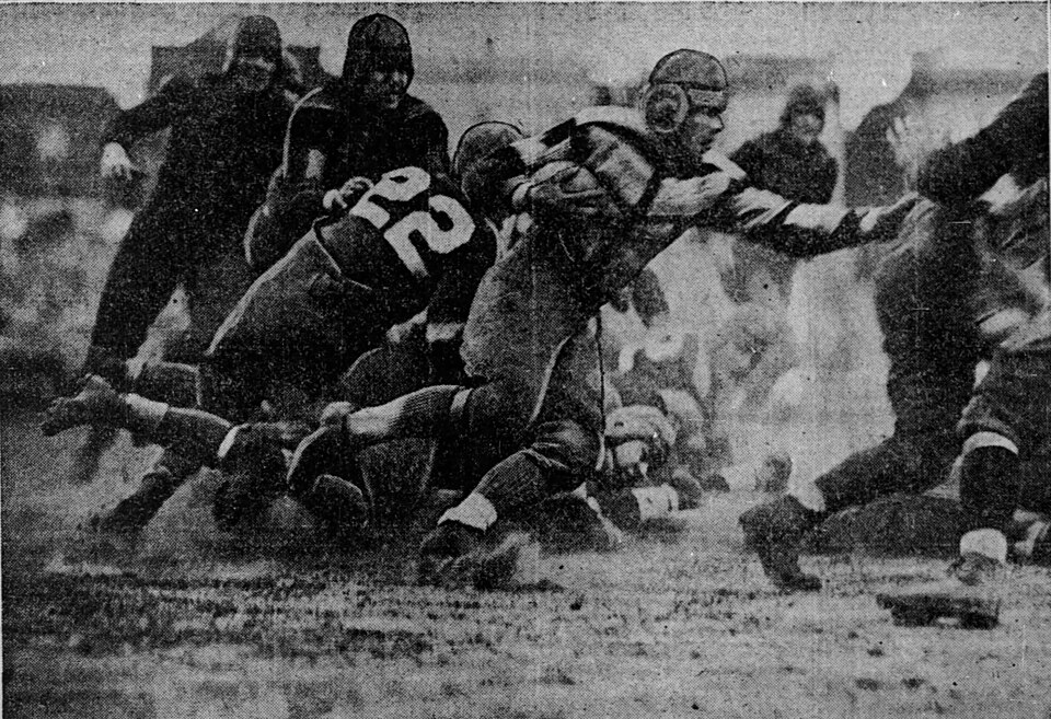Vintage newspaper photo clipping of Red Grange dashes through the Bear line in the second quarter of the Oct. 16, 1927 Chicago-New York football game at Wrigley Field. Chicago Tribune Oct 17 1927, courtesy of Wikimedia Commons.