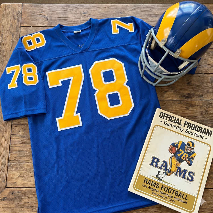 Image of a 1970s era NFL Los Angeles American football jersey 78, without a name on it, and matching blue helmet. The program cover should say Rams.