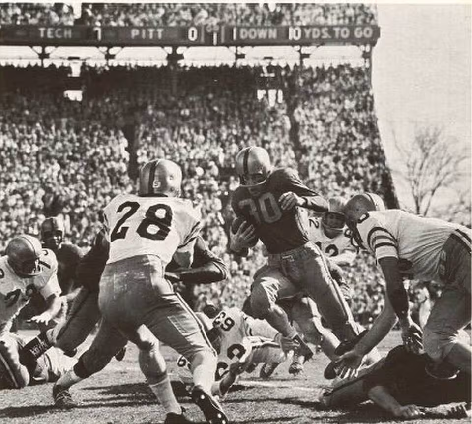 Vintage black and white game action image of the Pitt v/s Georgia Tech at the 1956 Sugar Bowl game, Tulane Stadium, New Orleans. "Pitt halfback Lou Cimarolli finds a hole in the strong Georgia Tech line and picks up 10 yards." Thomas C. Vrana, photographer for "The Owl."