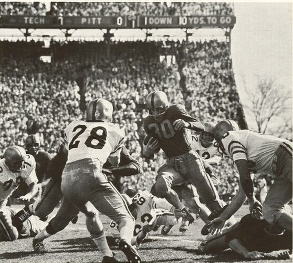 Vintage black and white game action image of the Pitt v/s Georgia Tech at the 1956 Sugar Bowl game, Tulane Stadium, New Orleans. "Pitt halfback Lou Cimarolli finds a hole in the strong Georgia Tech line and picks up 10 yards." Thomas C. Vrana, photographer for "The Owl."