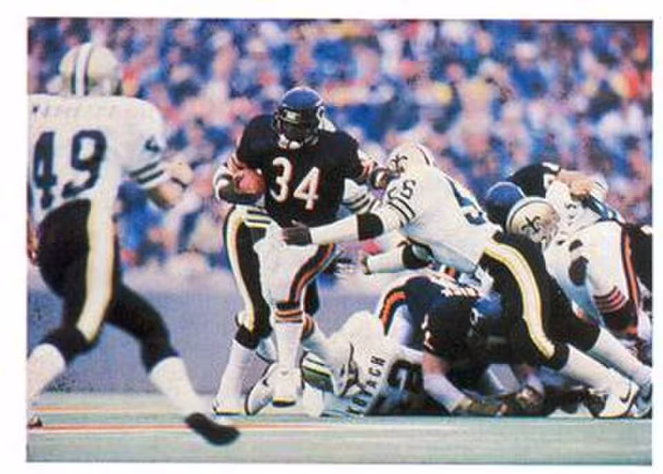 Full color game action image of Chicago Bears RB number 34 Walter Payton breaking tackles during a run against the New Orleans Saints.