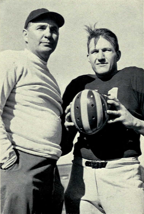 Vintage 1940s black-and-white photograph from Bennie_Oosterbaan_and_Alvin_Wistert.jpg featuring Michigan Wolverines head coach Bennie Oosterbaan in a baseball cap and sweatshirt standing next to All-American tackle Alvin Wistert. Wistert wears a dark jersey and holds a classic segmented, striped leather winged helmet. A primary source for Big Ten college football history and Pigskin Dispatch archives.