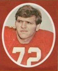 Red background with an oval publicity head shot of 1972 stamp of Dan Dierdorf for St. Louis Cardinals (NFL)