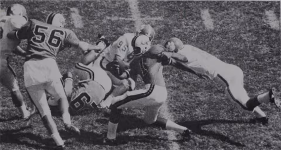 black and white game action photo of Eddie McAshan (No. 1), the quarterback for the Georgia Tech Yellow Jackets football team, is tackled by Jim Sursavage (No. 80), a linebacker for the Clemson Tigers football team, with assistance from defensive end Wayne Baker (No. 95) during the October 3, 1970, game between the two teams, held at Grant Field on Georgia Tech's campus in Atlanta.