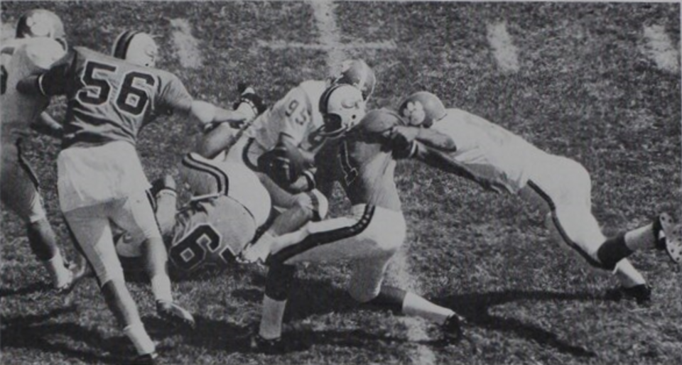 black and white game action photo of Eddie McAshan (No. 1), the quarterback for the Georgia Tech Yellow Jackets football team, is tackled by Jim Sursavage (No. 80), a linebacker for the Clemson Tigers football team, with assistance from defensive end Wayne Baker (No. 95) during the October 3, 1970, game between the two teams, held at Grant Field on Georgia Tech's campus in Atlanta.
