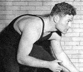 black and white image of Jack Riley as a wrestler at Northwestern University, in a wrestling pose.