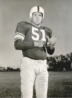 Vintage 1954 black-and-white promotional photograph from Kurt_Burris.png featuring Oklahoma Sooners All-American center Kurt Burris (#51) posing on a practice field. He wears a dark jersey with white block numbers and double sleeve stripes, light-colored pants, and a white molded plastic helmet with a dark center stripe and no facemask. A primary source for Big Seven college football history and Pigskin Dispatch archives.