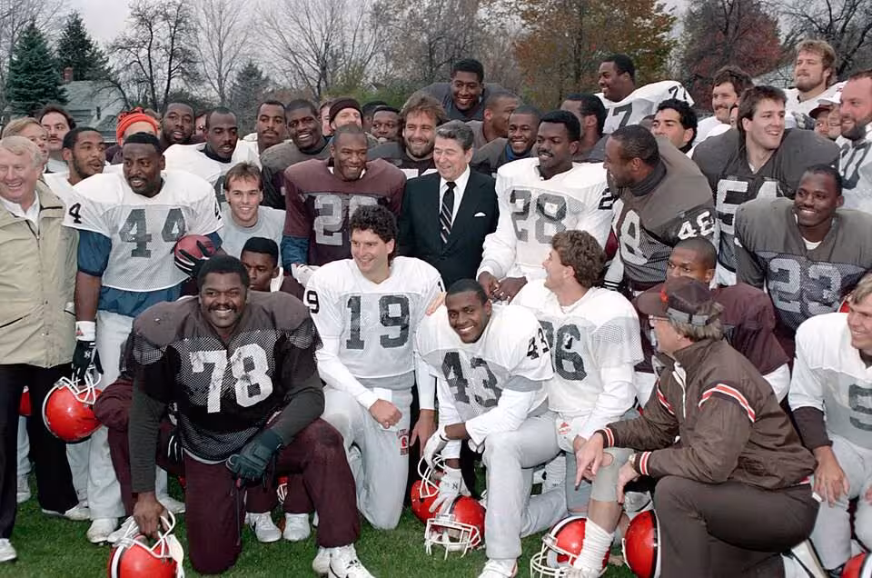 Full color publicity image of President Ronald Reagan during a trip to Ohio and a photo op with the Cleveland Browns football team at Baldwin Wallace College