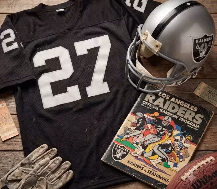 AI-generated black jersey 27 on a wooden table with a silver Raiders helmet and period example of a program