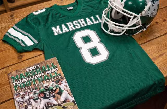AI-generated green Marshall jersey 8 on a wooden table with a green helmet and period example of a program