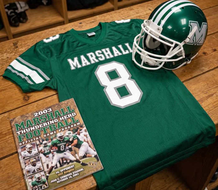 AI-generated green Marshall jersey 8 on a wooden table with a green helmet and period example of a program