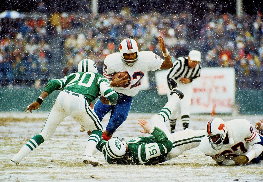 Full color game action photo of Simpson breaking the NFL's single-season rushing record in 1973