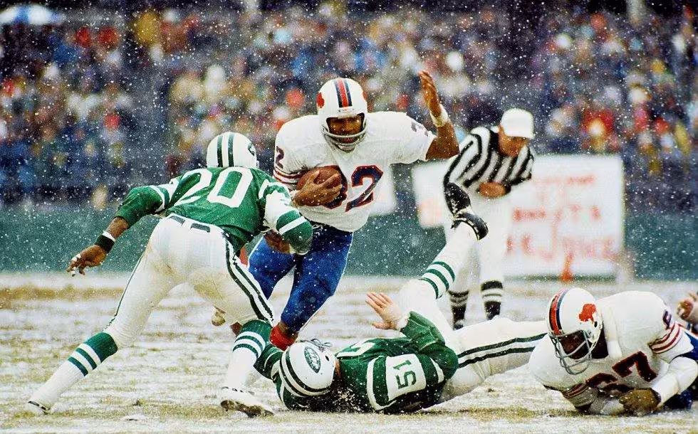 Full color game action photo of Simpson breaking the NFL's single-season rushing record in 1973