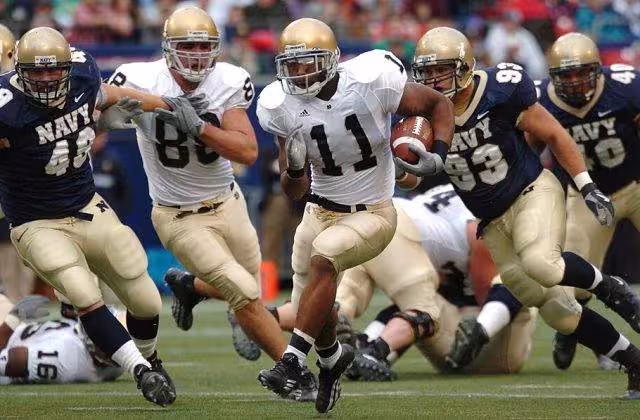 Full color game time action image of Notre Dame running back Marcus Wilson races for yardage as a trio of U.S. Naval Academy Midshipmen defenders gives chase at Giants Stadium in East Rutherford, N.J.