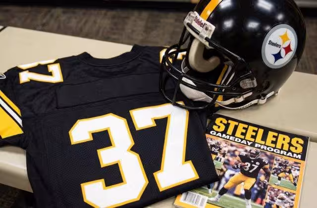 AI-generated black jersey 37 on a wooden table with a matching helmet and period example of a program