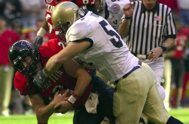full color game action photo of Navy linebacker Bobby McClarin sacks Texas Tech quarterback B.J. Symons during the EV1.Net en:Houston Bowl at en:Reliant Stadium in en:Houston, Texas. The Midshipmen of the U.S. Naval Academy lost to the Red Raiders, 38-14, leaving Navy with an 8-5 record on the year. Navy boasted the top rushing offense in Division 1-A, while Tech had the nation’s leading passing offense.