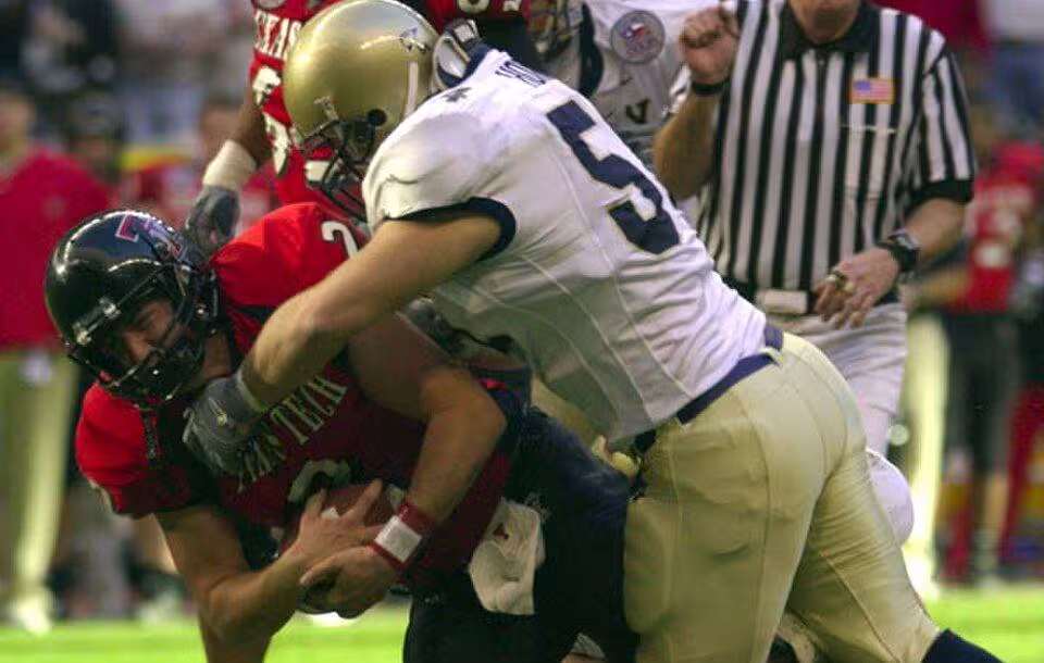 full color game action photo of Navy linebacker Bobby McClarin sacks Texas Tech quarterback B.J. Symons during the EV1.Net en:Houston Bowl at en:Reliant Stadium in en:Houston, Texas. The Midshipmen of the U.S. Naval Academy lost to the Red Raiders, 38-14, leaving Navy with an 8-5 record on the year. Navy boasted the top rushing offense in Division 1-A, while Tech had the nation’s leading passing offense.