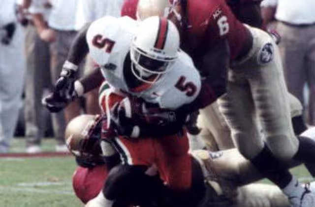 Full color game action photo of Miami Hurricanes running back Edgerrin James being tackled by an Florida State Seminoles defenders Derrick Gibson (6) and an unidentified player at Doak Campbell Stadium - Tallahassee, Florida