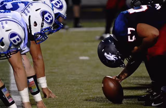 Full color image pre-snap down the line of scrimmage for A December 14, 2015 photo by Nathan Shively of Football players on field (Unsplash)