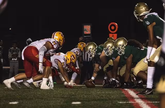 Full color game action at the line of scrimmage, presnap of Football players from the Mission Viejo and Long Beach Polytechnic High School football teams prepare to snap the ball during a football game at the Veterans Memorial Stadium, Long Beach, California, Sept. 3, 2021. The Great American Rivalry Series, presented by the United States Marine Corps, features some of the longest-running and most tradition-filled rivalries in high school football across the nation. (U.S. Marine Corps photo by Sgt. Christian Cachola)