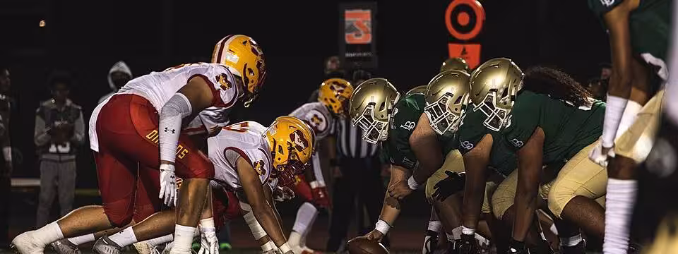 Full color game action at the line of scrimmage, presnap of Football players from the Mission Viejo and Long Beach Polytechnic High School football teams prepare to snap the ball during a football game at the Veterans Memorial Stadium, Long Beach, California, Sept. 3, 2021. The Great American Rivalry Series, presented by the United States Marine Corps, features some of the longest-running and most tradition-filled rivalries in high school football across the nation. (U.S. Marine Corps photo by Sgt. Christian Cachola)