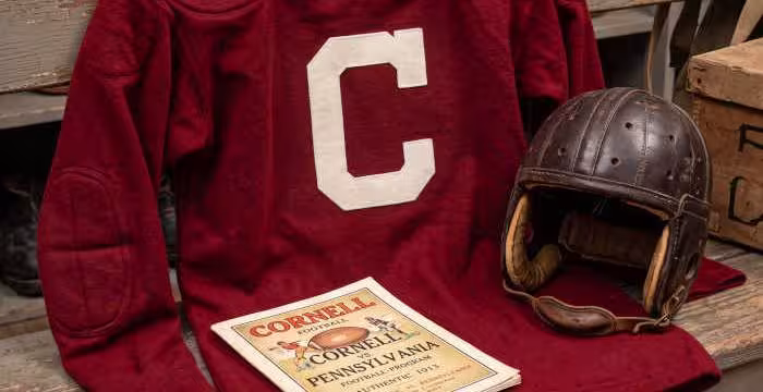Gemini AI generated image of a 1913 era red American football jersey, without a name on it, and a matching period-correct helmet, the program cover appropriate to the era and team.