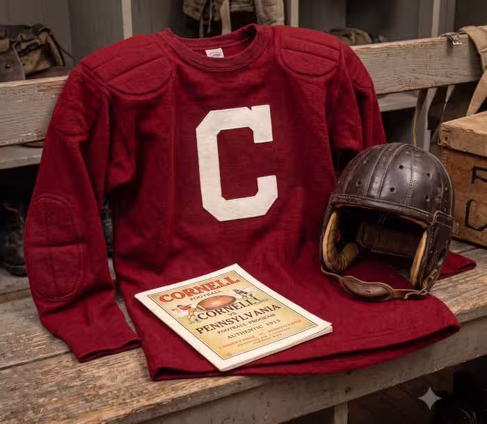 Gemini AI generated image of a 1913 era red American football jersey, without a name on it, and a matching period-correct helmet, the program cover appropriate to the era and team.