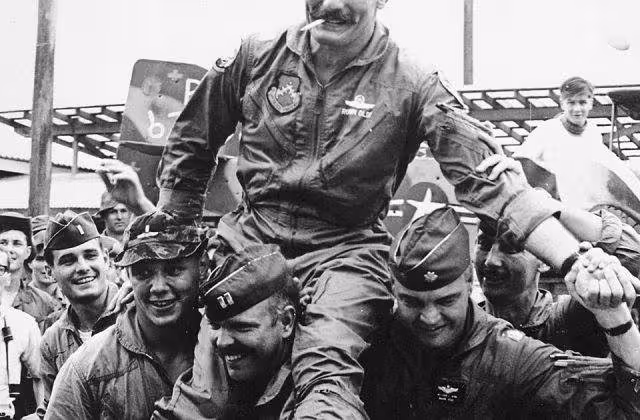 Black and white USAF photo of "Wolfpack" aviators of the 8th Tactical Fighter Wing carry their commanding officer, Colonel Robin Olds, following his return from his last combat mission over North Vietnam, on 23 September 1967