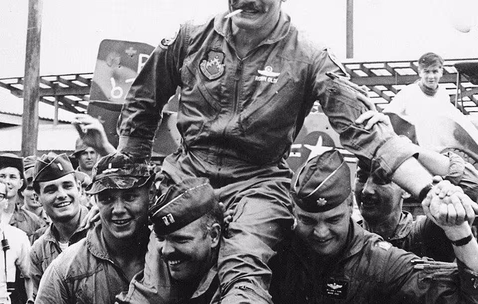 Black and white USAF photo of "Wolfpack" aviators of the 8th Tactical Fighter Wing carry their commanding officer, Colonel Robin Olds, following his return from his last combat mission over North Vietnam, on 23 September 1967