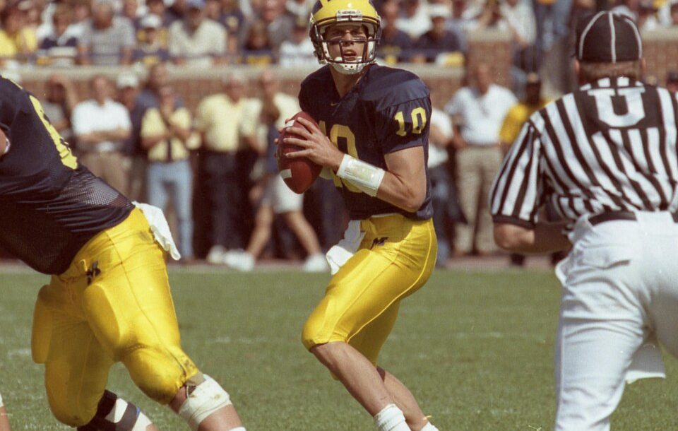1999 game action photo of Tom Brady, quarterback for the Michigan Wolverines. Wikimedia Commons by uploader Robert Kalmbach, under Creative Commons Attribution 4.0