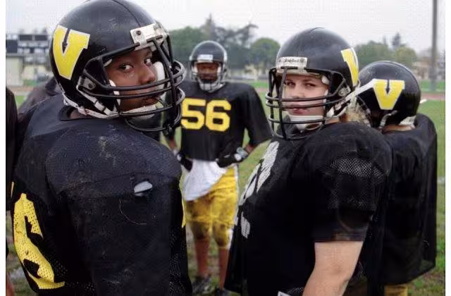Color image photo of U.S. Department of Defense Dependents Schools (DoDDS) sponsor a wide range of sports activities for its students. Vicenza American High School students at football practice on Caserma Ederle, Italy (October 2002). The team featured a female center (pictured right). Photo by Peter Rimar.