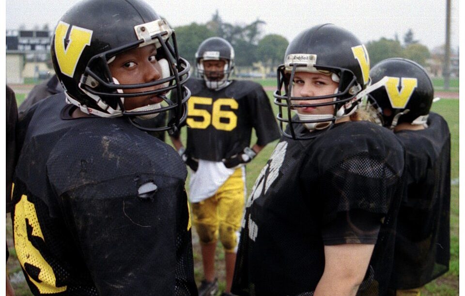 Color image photo of U.S. Department of Defense Dependents Schools (DoDDS) sponsor a wide range of sports activities for its students. Vicenza American High School students at football practice on Caserma Ederle, Italy (October 2002). The team featured a female center (pictured right). Photo by Peter Rimar.