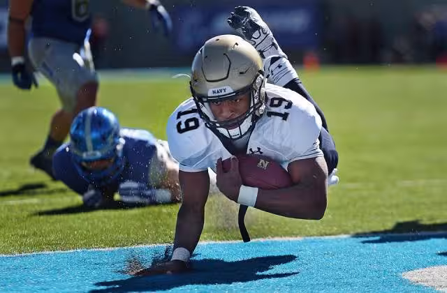 Full color game action photo of Navy quarterback Keenan Reynolds lands in the end zone for a touchdown against Air Force at the Air Force Academy in Colorado Springs, Colo. Oct. 4, 2014. Air Force won the game, which honored the athletes in the 2014 Warrior Games. (DoD News photo by EJ Hersom)