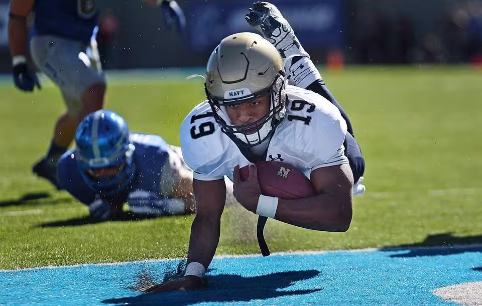 Full color game action photo of Navy quarterback Keenan Reynolds lands in the end zone for a touchdown against Air Force at the Air Force Academy in Colorado Springs, Colo. Oct. 4, 2014. Air Force won the game, which honored the athletes in the 2014 Warrior Games. (DoD News photo by EJ Hersom)