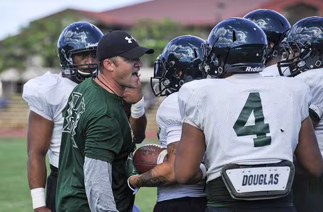 Chris Wiesehan, left, an assistant coach for the University of Hawaii football team, runs a drill during a practice at Joint Base Pearl Harbor-Hickam Aug. 15, 2013, in Hawaii. The practice took place on Earhart Field which overlooks the Hickam Field flight line where active military jets and commercial aircraft constantly take off and land. MCSN Johans Chavarro
