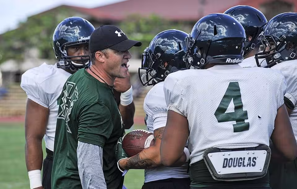 Chris Wiesehan, left, an assistant coach for the University of Hawaii football team, runs a drill during a practice at Joint Base Pearl Harbor-Hickam Aug. 15, 2013, in Hawaii. The practice took place on Earhart Field which overlooks the Hickam Field flight line where active military jets and commercial aircraft constantly take off and land. MCSN Johans Chavarro