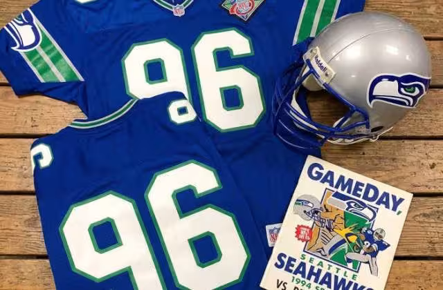 Gemini AI created image of a 1994-era Seattle NFLy American football jersey 96, without a name on it, and a matching period-correct helmet, the program cover appropriate to the era and team.