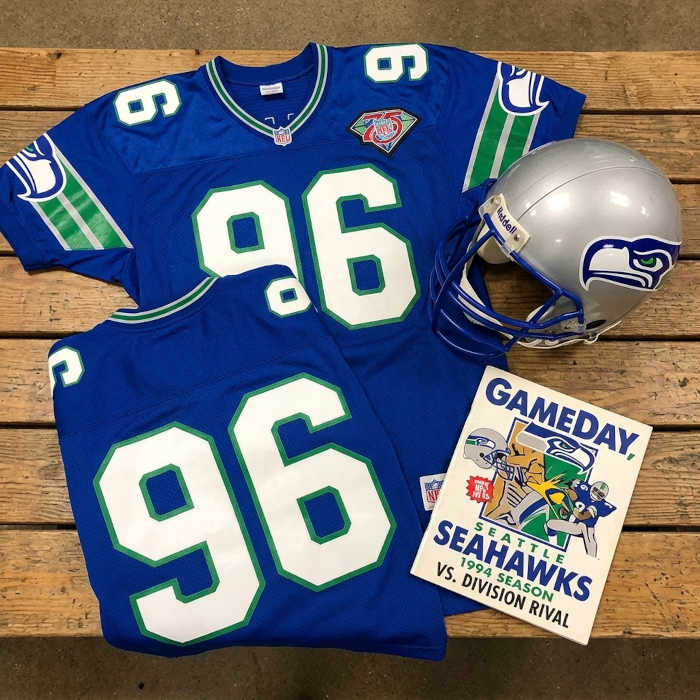 Gemini AI created image of a 1994-era Seattle NFLy American football jersey 96, without a name on it, and a matching period-correct helmet, the program cover appropriate to the era and team.