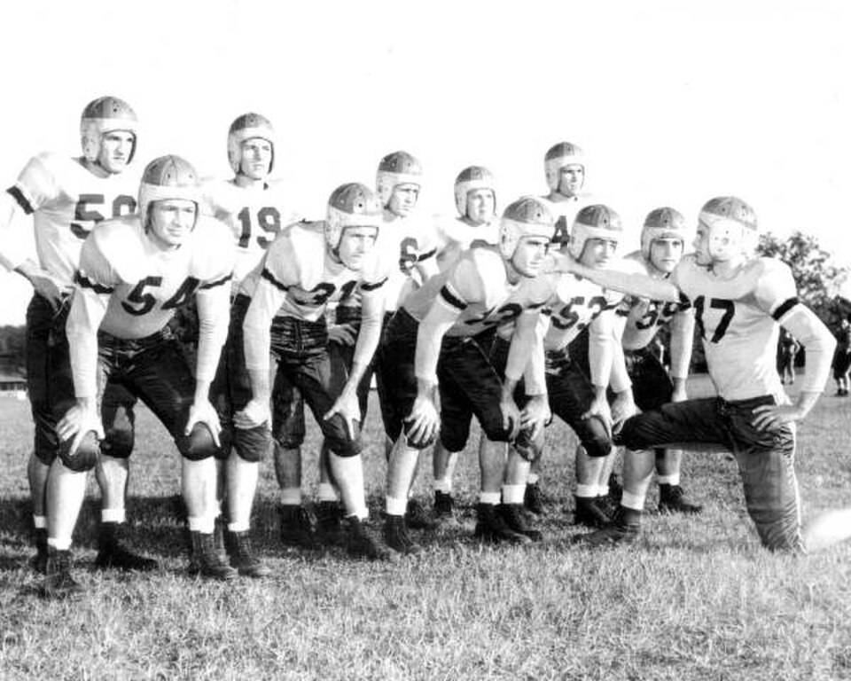 Black and white posed team huddle of Florida State University football squad: Tallahassee, Florida Date: 1947