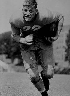 B/W publicity photo of George Cafego in uniform carrying the ball.