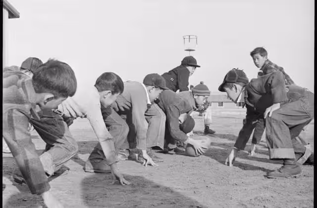 Black and white image, Granada Relocation Center, Amache, Colorado. Grade school boys playing touch football during the recess play period.Courtesy of Wikimedia Commons uploader, Tom Parker.