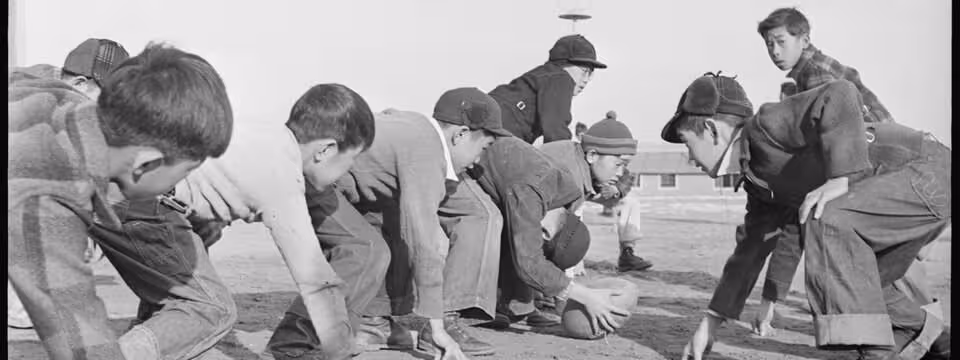 Black and white image, Granada Relocation Center, Amache, Colorado. Grade school boys playing touch football during the recess play period.Courtesy of Wikimedia Commons uploader, Tom Parker.