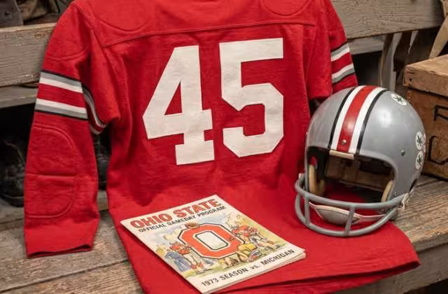 Gemini AI-created image of a 1973-era Ohio State University American football jersey 45, without a name on it, and a matching period-correct helmet, the program cover appropriate to the era and team.