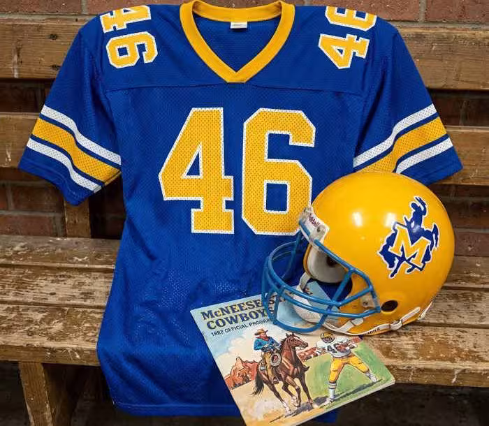 Gemini AI-created image of a 1982-era McNeese State American football jersey 46, without a name on it, and a matching period-correct helmet, the program cover appropriate to the era and team.